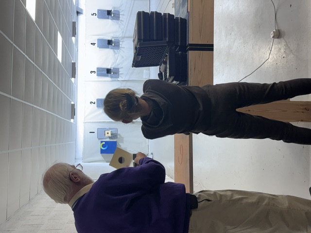 A coach talks a young shooter through her target card